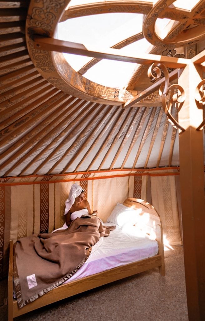 Girl reading a book in bed in a Mongolian yurt